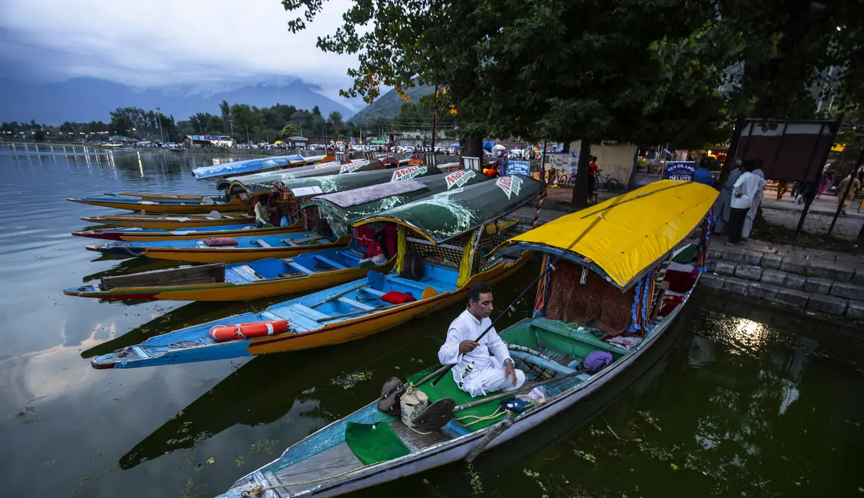 Seorang tukang perahu Kashmir memancing di tepi Danau Dal di Srinagar, Kashmir yang dikuasai India, Minggu (1/8/2021). Di Sepanjang tepi Danau Dal terdapat Ghate yang merupakan tempat bersandarnya Shikara. (AP Photo/Mukhtar Khan)