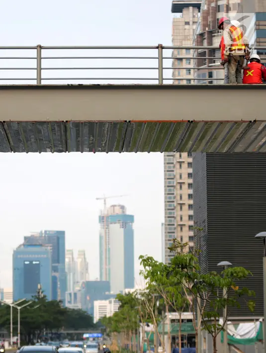 Pekerja menyelesaikan revitalisasi Jembatan Penyeberangan Orang (JPO) Gelora Bung Karno (GBK), Jakarta, Selasa (27/11). Pemprov DKI Jakarta merevitalisasi tiga JPO di Polda Metro Jaya, GBK dan Bundaran Senayan. (Liputan6.com/Faizal Fanani)