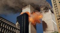 Asap mengepul dari salah satu menara World Trade Center saat api dan puing-puing meledak dari menara kedua (AP Photos/Chao Soi Cheong)