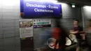 Para komuter berjalan dekat tanda yang bertuliskan "Deschamps - Elysees Clemenceau" di stasiun metro Champs - Elysees Clemenceau, Paris, Senin (16/7). Hal itu untuk merayakan kesuksesan timnas Prancis menjadi juara Piala Dunia. (AFP/Thomas SAMSON)