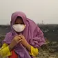 Seorang anak mengenakan masker saat bermain di lokasi lahan perusahaan bekas kebakaran hutan di wilayah Kumpeh, Muaro Jambi. Foto diambil tahun 2019. (Liputan6.com / Gresi Plasmanto)