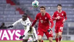 Penyerang Bayern Munchen, Thomas Mueller, berebut bola dengan pemain Hoffenheim, Diadie Samassekou, pada laga Bundesliga di Stadion Allianz Arena, Sabtu (30/1/2021). Bayern Munchen menang dengan skor 4-1. (Sven Hoppe/dpa via AP)