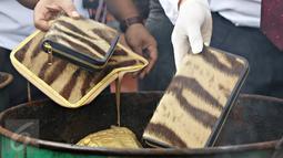 Petugas membakar dompet kulit harimau saat pemusnahan barang bukti bagian hewan yang dilindungi, Jakarta, Selasa (2/2). Barbuk berupa kulit, tulang dan taring harimau, kerapas penyu, off set penyu dan kulit buaya (Liputan6.com/Immanuel Antonius)