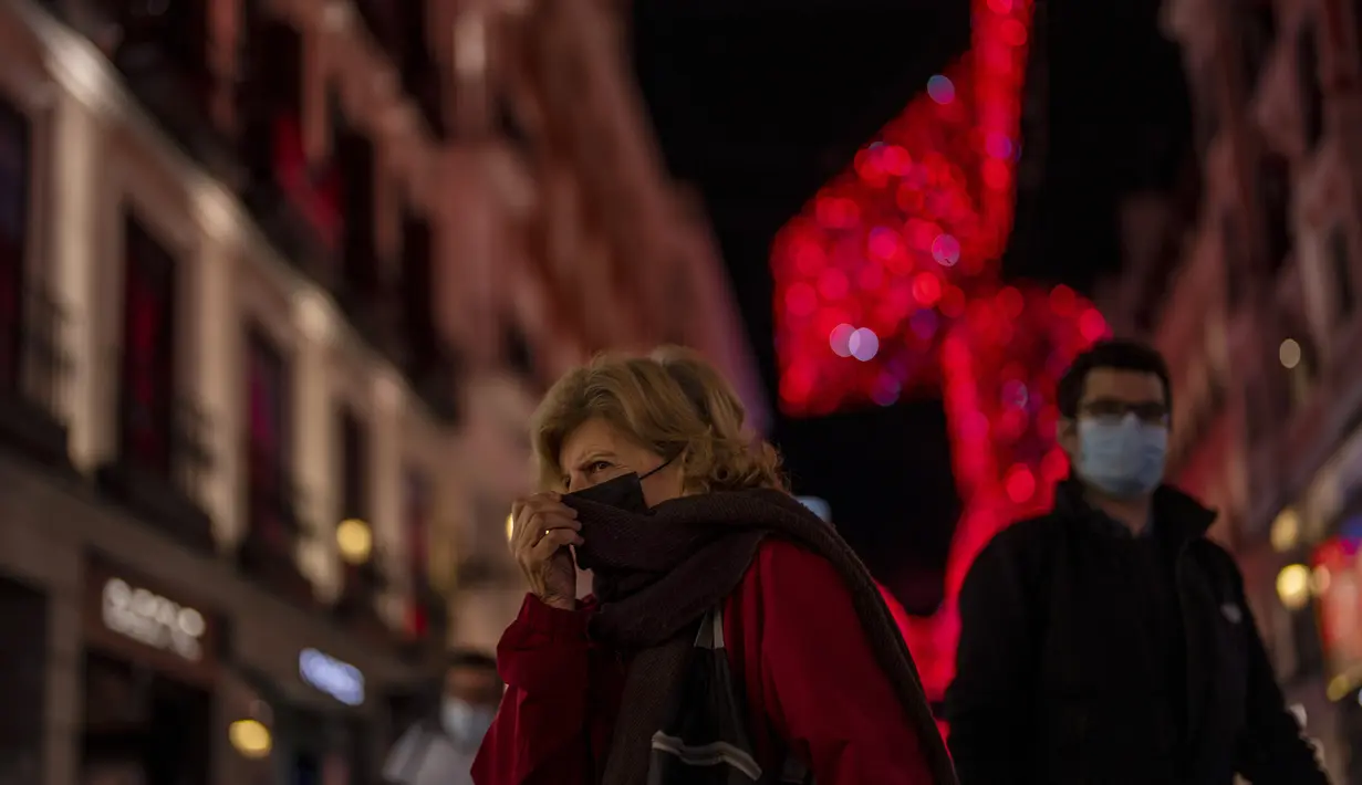 Orang-orang yang memakai masker berjalan di pusat kota Madrid, Rabu (22/12/2021). Perdana Menteri Spanyol Pedro Sanchez mengadakan rapat Kabinet khusus untuk mengesahkan undang-undang yang mewajibkan penggunaan masker di luar ruangan di tengah lonjakan rekor kasus COVID-19. (AP Photo/Manu Fernandez)