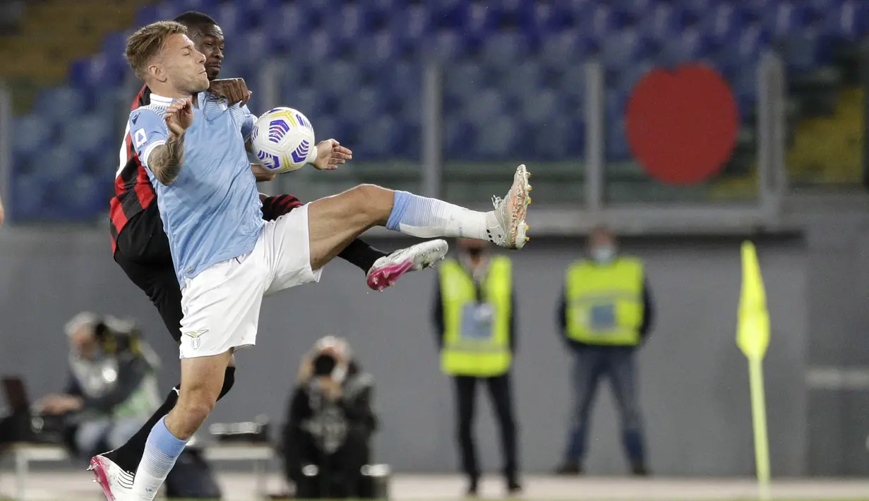 Bek AC Milan, Fikayo Tomori bersaing memperebutkan bola dengan penyerang Lazio, Ciro Immobile dalam laga pekan ke-33 Liga Italia 2020-2021 di Stadio Olimpico, Selasa dinihari WIB (27/4/2021). AC Milan kalah telak 3-0 saat menyambangi kandang Lazio. (AP Photo/Gregorio Borgia)