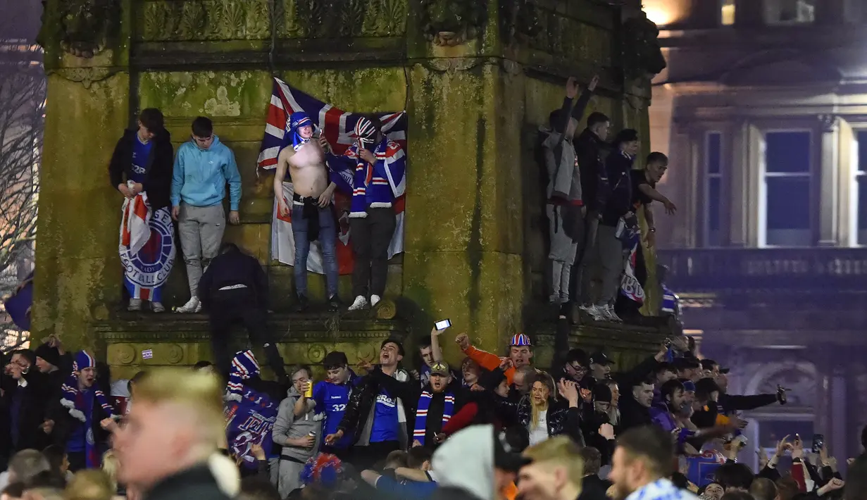 Para fans Glasgow Rangers memadati George Square, pusat kota Glasgow (7/3/2021) untuk merayakan keberhasilan tim kesayangan mereka merebut gelar Liga Utama Skotlandia setelah memimpin 20 poin dari saingan terdekat, Glasgow Celtic. (AFP/Andy Buchanan)