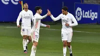 Pemain Real Madrid, Raphael Varane (kanan) berselebrasi bersama Marco Asensio (tengah), dan Casemiro setelah mencetak gol ke gawang Huesca pada laga La Liga di Stadion El Alcoraz, Sabtu (6/2/2021). (AFP/Pau Barrena)