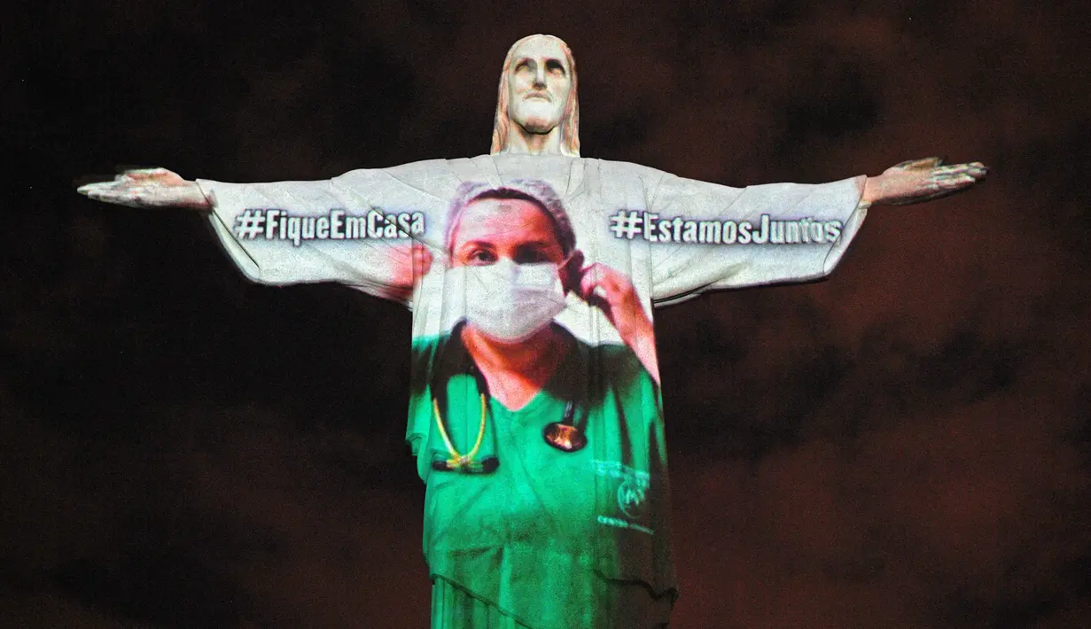 Patung Christ the Redeemer atau Yesus sang Penebus yang populer di dunia menyala dengan gambar tenaga medis pada Paskah di Rio de Janeiro, Brasil, Minggu (12/4/2020). Pertunjukkan itu bentuk solidaritas kepada dokter dan perawat yang telah merawat pasien corona di berbagai negara. CARL DE SOUZA/AFP)