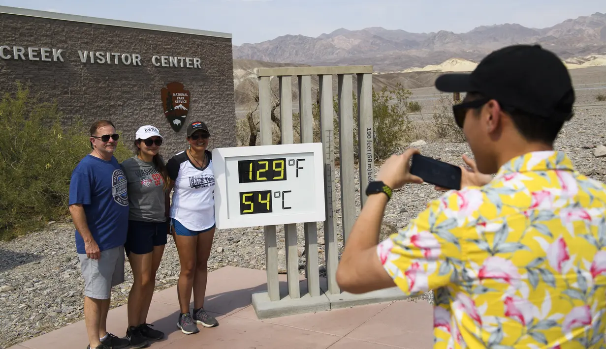 Turis berpose dekat termometer yang menunjukkan suhu 129 Derajat Fahrenheit (54 Derajat Celcius) di Pusat Pengunjung Furnace Creek di Taman Nasional Death Valley, California, Kamis (17/6/2021). Sebagian besar AS bagian barat bersiap menghadapi rekor gelombang panas minggu ini. (Patrick T. FALLON/AFP