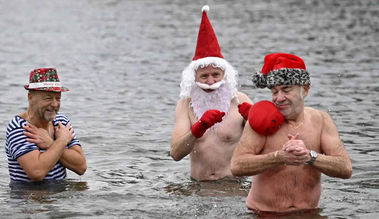 Anggota klub renang "Berliner Seehunde" (Berlin Seals) berendam di Danau Orankesee, Berlin, Minggu (25/12). Kegiatan yang sudah menjadi tradisi ini merupakan bagian dari perayaan tradisional Natal bagi warga Berlin. (Tobias SCHWARZ / AFP)