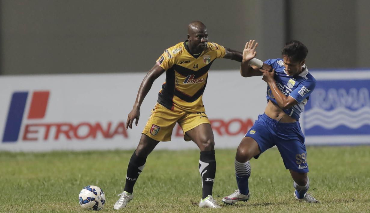 Pemain Persib, Yandi Sofyan berusaha merebut bola dari Pemain Mitra Kukar, O.K John pada leg pertama semi final Piala Presiden di Stadion Aji Imbut, Tenggarong, Minggu (4/10/2015). (Bola.com/Vitalis Yogi Trisna)