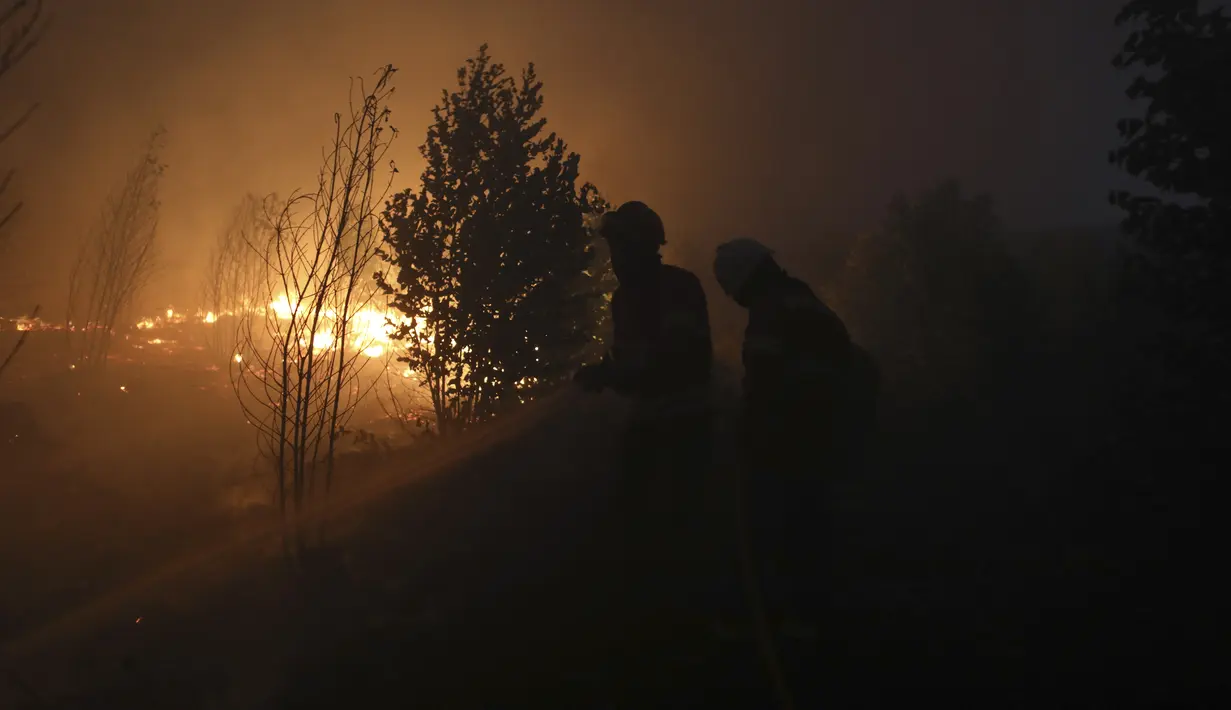 Petugas pemadam kebakaran berusaha memadamkan kebakaran hutan di daerah Rio Maior di Portugal, Rabu (17/8/2022). Namun, para pejabat memperingatkan perkiraan gelombang panas baru untuk daerah tersebut dapat memperumit tugas tersebut. (AP Photo/Joao Henriques)