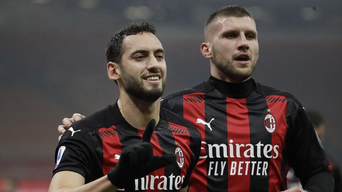 Gelandang AC Milan, Hakan Calhanoglu (kiri) berselebrasi usai mencetak gol ke gawang Lazio di menit ke-17 pada pertandingan lanjutan Liga Serie A Italia di stadion San Siro, Italia, Kamis (24/12/2020). (AP Photo/Luca Bruno)