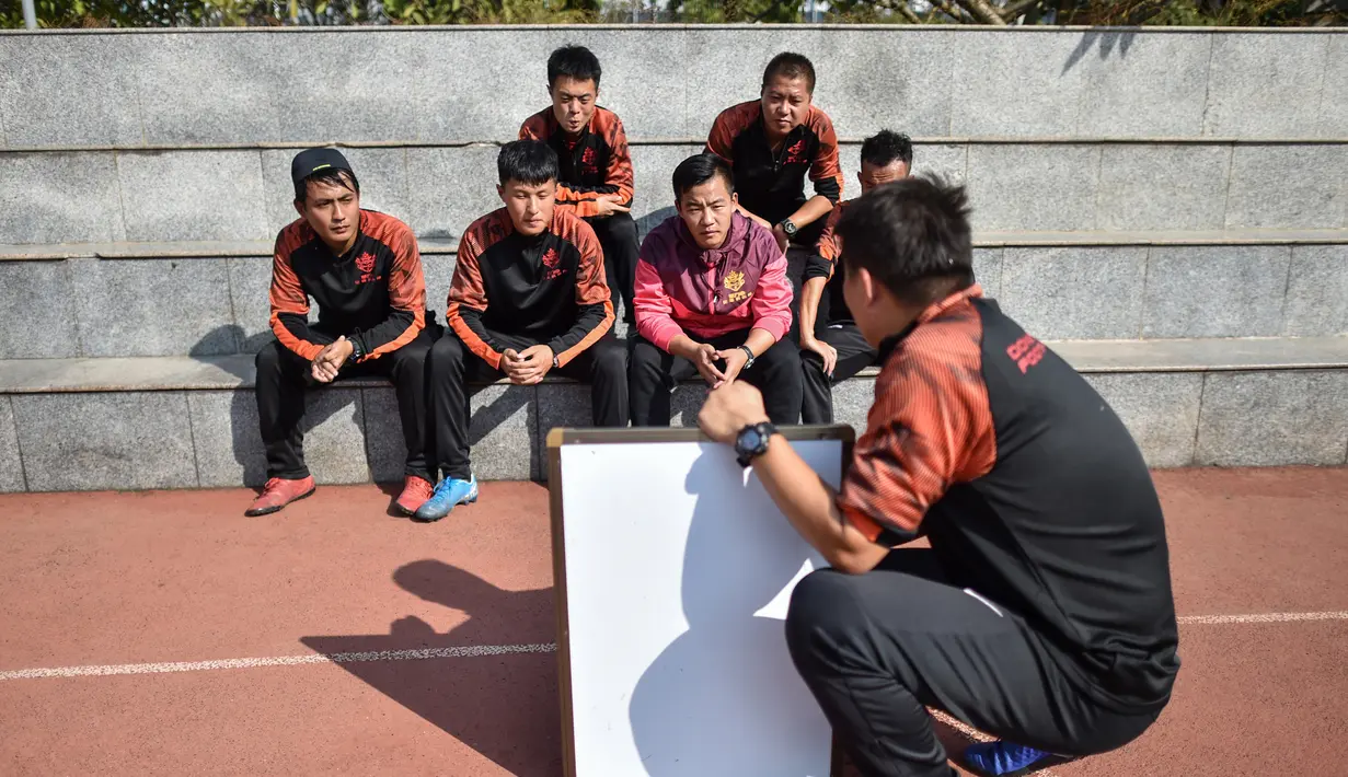 Mantan penyerang Manchester United, Dong Fangzhuo (depan) berbicara dengan pelatih lain dari klub sepak bola Dong Fangzhuo, di Xiamen, Fujian, China (10/12/2019). Dong Fangzhuo yang kini berusia 34 tahun melatih anak-anak di China, beberapa di antaranya berkebutuhan khusus. (AFP/Hector Retamal)