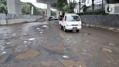Kendaraan melintas dekat jalan berlubang di kawasan Kelapa Gading, Jakarta, Minggu (1/3/2020). Kepala Dinas Bina Marga DKI Jakarta Hari Nugroho mengatakan banjir pada Februari 2020 merusak 495 jalan Ibu Kota dengan 3.290 titik lubang yang tersebar di lima wilayah. (merdeka.com/Iqbal Nugroho)