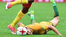 Pemain Australia, Mathew Leckie terjatuh saat berduel dengan pemain Kamerun pada laga grup B Piala Konfederasi 2017 di Saint Petersburg Stadium, (22/6/2017). (AFP/Mladen Antonov)