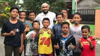 Kiper Persebaya Surabaya, Alfonsius Kelvan, foto bareng anak-anak yang tinggal di kediaman orang tuanya di kawasan Tanggulangin, Sidoarjo, Jawa Timur. (Bola.com/Aditya Wany)