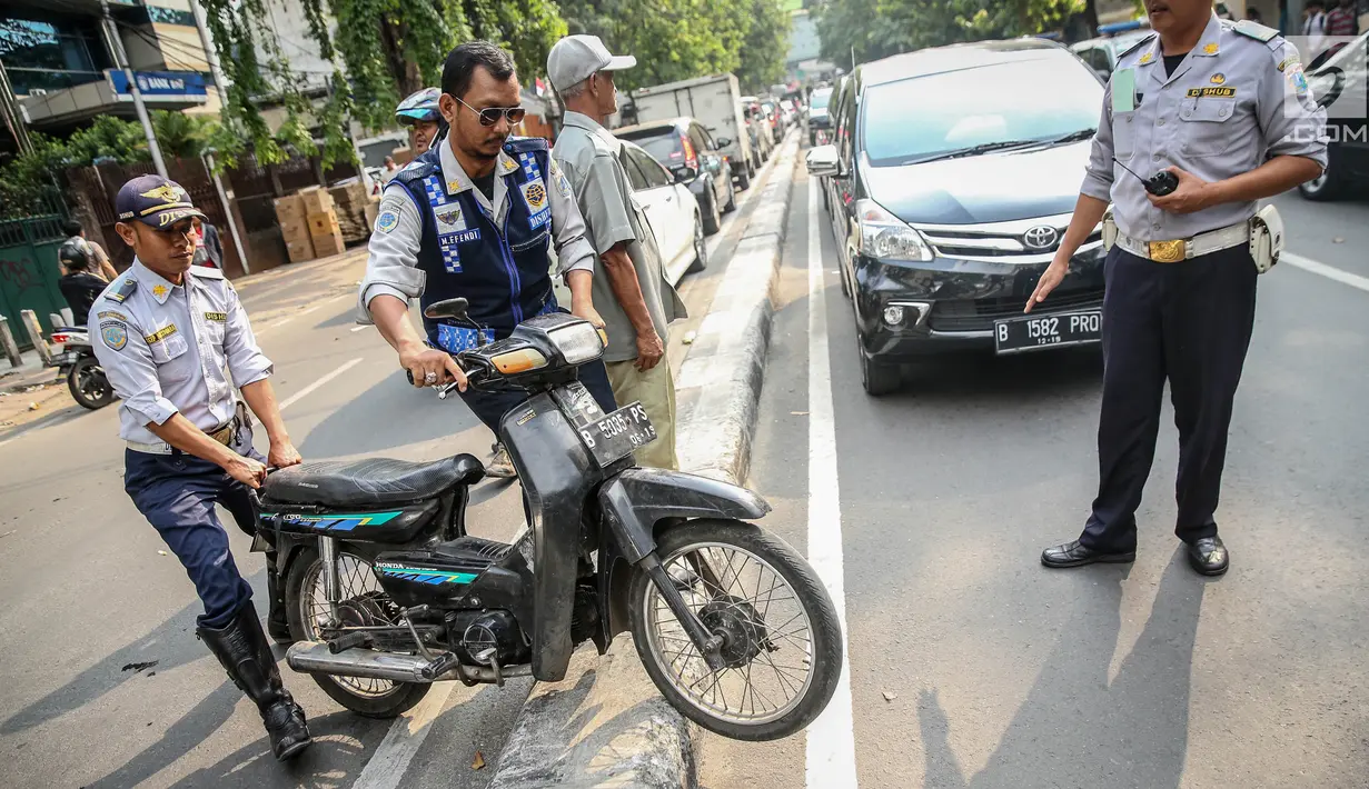 Petugas Dishub mengangkut sepeda motor saat melakukan penertiban parkir liar di atas trotoar kawasan KH Wahid Hasyim, Jakarta, Selasa (1/8). Penertiban dalam rangka 'Bulan Patuh Trotoar' itu untuk mengembalikan fungsi trotoar. (Liputan6.com/Faizal Fanani)