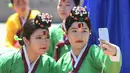 Dua gadis Korea Selatan berselfie saat mengikuti upacara Coming of Age Day di desa Hanan Namsan di Seoul (21/5). (AFP Photo/Jung Yeon-je)