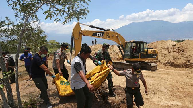 Petugas membawa jenazah korban gempa dan tsunami untuk dimakamkan massal di Palu, Sulawesi Tengah, Senin (1/10). Gempa dan tsunami yang melanda Palu serta Donggala telah menewaskan ratusan korban jiwa. (AP Photo/Tatan Syuflana)