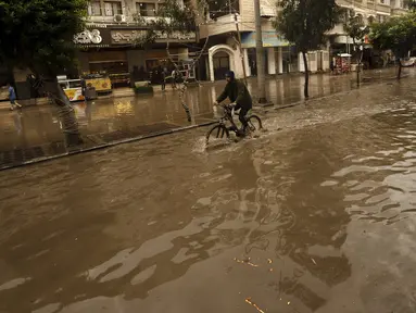 Seorang pemuda mengendarai sepedanya di jalan yang banjir saat hujan lebat di Kota Gaza, Selasa (8/11/2022). Hujan deras menyebabkan banjir bandang di Jalur Gaza pada hari Selasa, di mana infrastruktur yang bobrok sering membuat air banjir tidak surut, memperpanjang kerusakan. (AP Photo/Adel Hana)