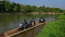 Warga bersama sepeda motornya menyeberangi Sungai Cisadane menggunakan rakit bambu di kawasan Ciseeng, Kabupaten Bogor, Jawa Barat, Kamis (11/6/2026). (merdeka.com/Arie Basuki)