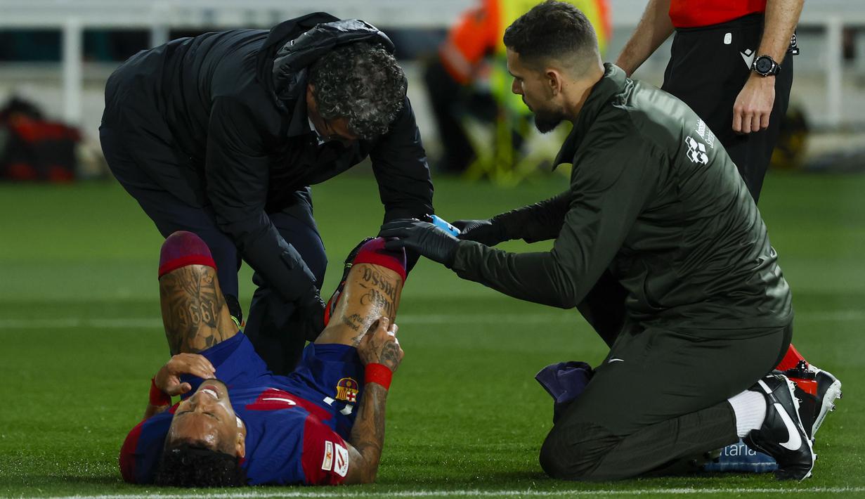 Striker Barcelona, Raphinha mendapat perawatan medis setelah mengalami cedera saat menghadapi Mallorca pada laga pekan ke-28 LaLiga 2023/2024 yang berlangsung di Olimpic Lluis Companys Stadium, Barcelona, Sabtu (9/3/2024) dini hari WIB. (AP Photo/Joan Monfort)