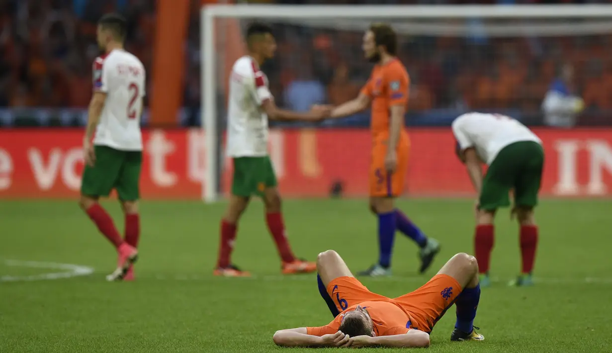Penyerang Belanda, Vincent Janssen menikmati kemenangan atas Bulgaria di atas dengan berbaring di atas rumput pada laga grup A kualifikasi Piala Dunia 2018 di Amsterdam, (3/9/2017). Belanda menang 3-1. (AFP/John Thys)