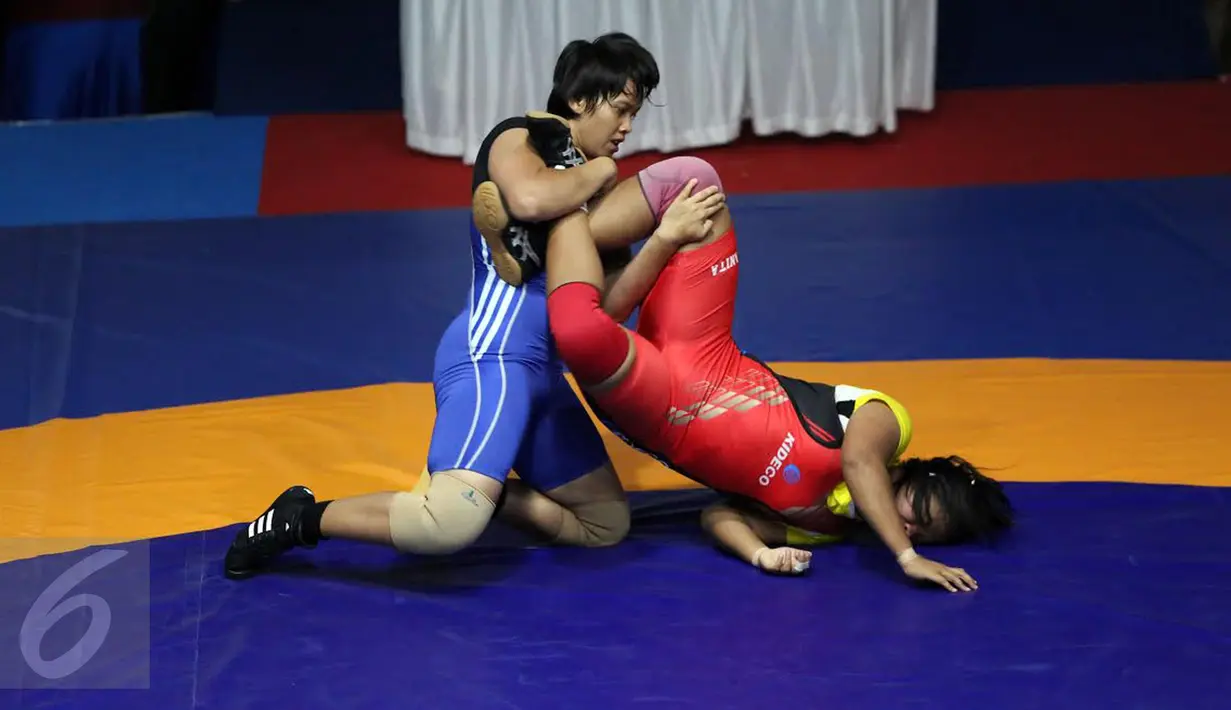 Pegulat putri Kalimantan Selatan Ridha W (biru) mengunci kaki Anita (Kaltim) saat laga final gaya bebas kelas 63 kg putri melawan Anita (Kaltim) pada PON XIX di Arena Saparua Sport Park, Bandung, Sabtu (24/9). (Liputan6.com/Helmi Fithriansyah)