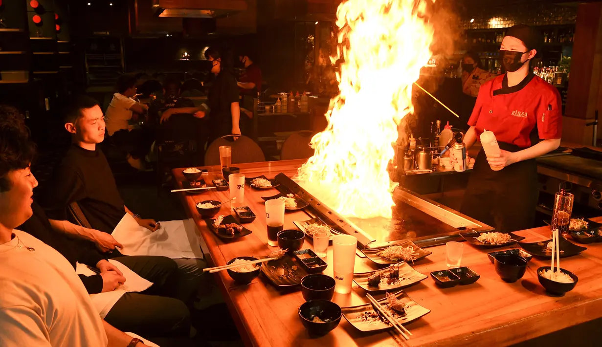 Pengunjung menikmati hidangan teppanyaki Jepang di Chinatown, Melbourne, Australia, Jumat (22/10/2021). Melbourne melonggarkan kebijakan lockdown mulai hari ini setelah berlangsung lebih dari 260 hari. (William WEST/AFP)