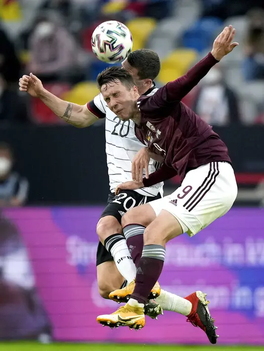 Bek timnas Jerman, Robin Gosens dan gelandang Latvia, Davis Ikaunieks bersaing dalam laga uji coba jelang EURO 2020 di Merkur Spiel Arena, Selasa (8/6/2021) dini hari WIB. Timnas Jerman memenangkan pertandingan dengan skor 7-1 atas timnas Latvia. (AP Photo/Martin Meissner)
