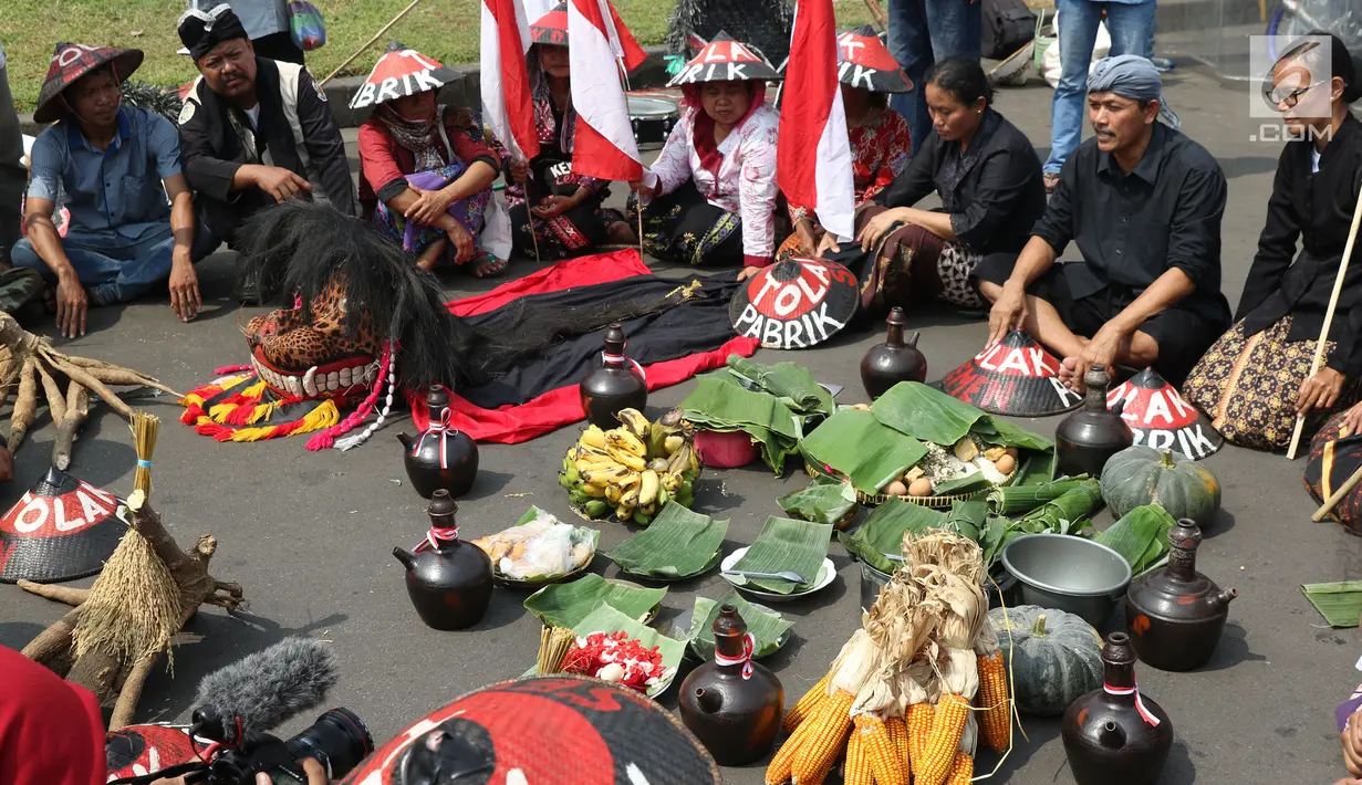 Sejumlah petani Kendeng berdoa saat aksi di depan Istana Negara, Jakarta, Kamis (2/8). Dalam aksinya, mereka melakukan tradisi Brokohan atau makan bersama nasi aneka urap yang sebelumnya didoakan. (Liputan6.com/Helmi Fithriansyah)