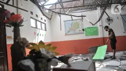 Penjaga sekolah berada di salah satu ruang kelas yang rusak akibat terjangan angin kencang di Sekolah Dasar Negeri (SDN) Pancoranmas 3, Depok, Jawa Barat, Minggu (24/7/2022). Puing-puing sisa bangunan yang ambruk pun masih berserakan di ruang kelas. (merdeka.com/Iqbal S. Nugroho)