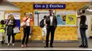 Calon penumpang mengambil gambar tanda bertuliskan "On a deux etoiles" di stasiun metro Etoile, Paris, Senin (16/7). Enam stasiun utama di Paris untuk sementara diganti namanya guna menghormati Prancis yang menjadi juara Piala Dunia. (AFP/Thomas SAMSON)