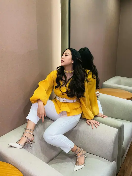 Penampilan bold Sherina Munaf degnan atasan berwarna kuning terang. Ia padukan dengan celana panjang putih, heels, dan belt putih yang serasi. [Foto: Instagram/sherinamunaf]