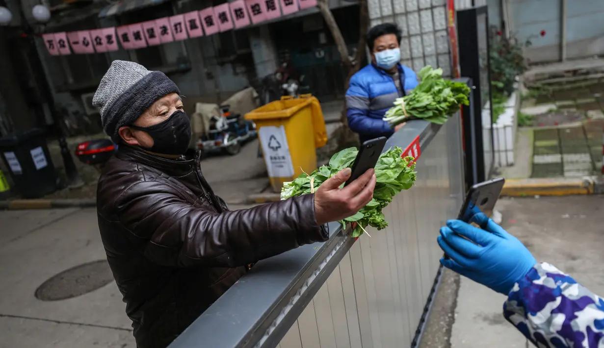 Seorang penduduk membayar sayur-sayuran di atas gerbang di Wuhan di provinsi Hubei tengah China (3/3/2020). Hingga saat ini, jumlah total kasus virus corona secara global dilaporkan mencapai 89.770 kasus yang tersebar di sekitar 70 negara termasuk Indonesia. (AFP/STR)