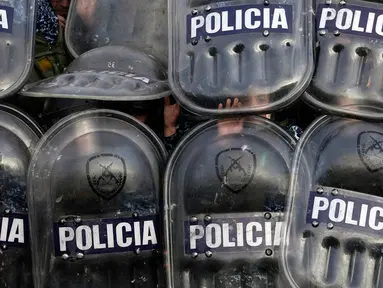 Polisi berlindung menggunakan perisai saat para demonstran melempari mereka dengan batu saat protes terhadap kematian gadis berusia 11 tahun Morena Dominguez di luar kantor polisi di pinggiran Buenos Aires, Argentina, Rabu (9/8/2023). (AP Photo/Natacha Pisarenko)