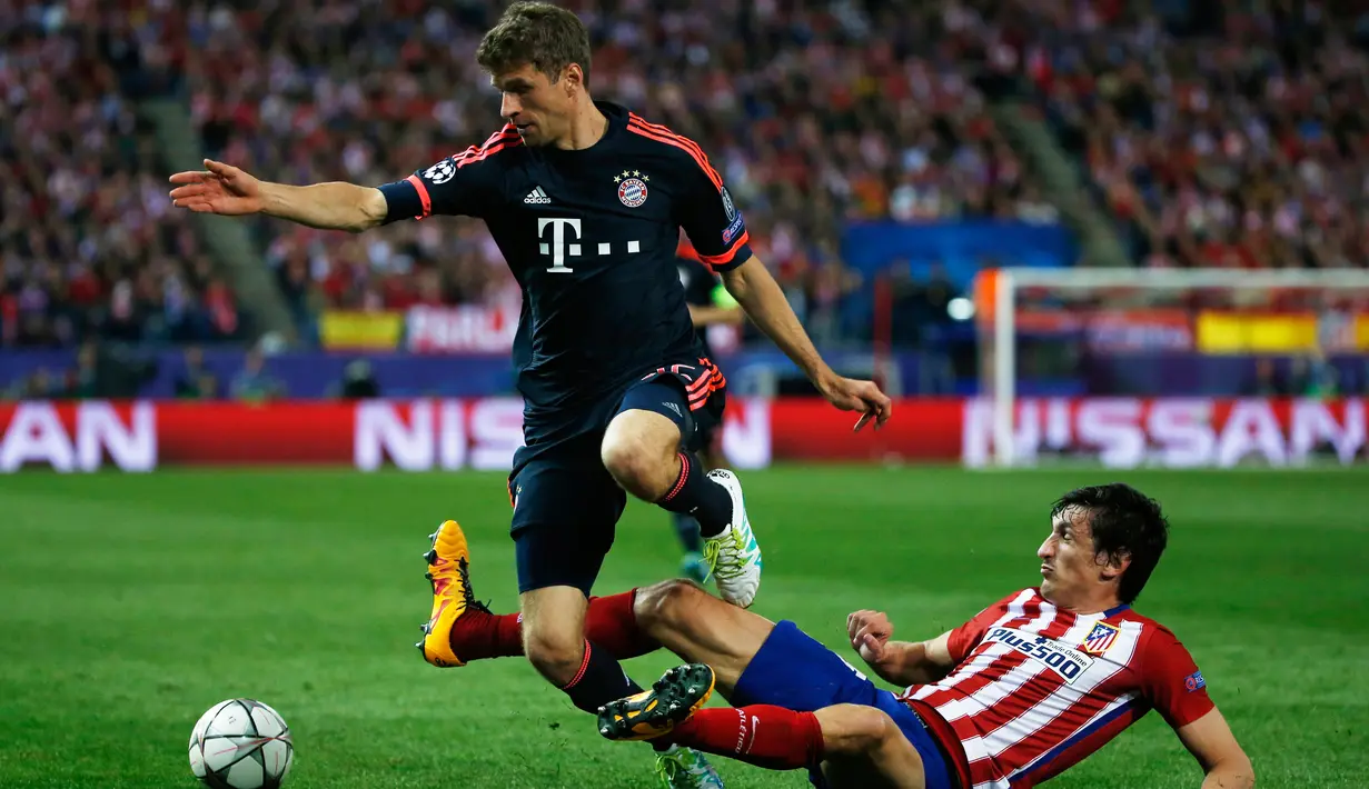 Penyerang Bayern Munchen, Thomas Muller (kiri) berusaha melewati bek Atletico Madrid, Stefan Savic di leg pertama liga champions di Vicente Calderon, Madrid, (28/4). Atletico menang atas Muenchen dengan skor 1-0. (Reuters/Sergio Perez)