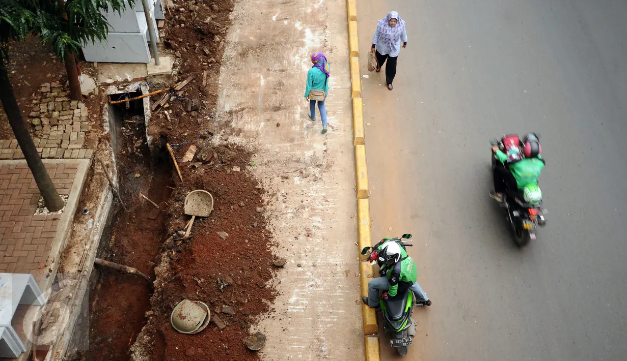Warga melintas di sisi proyek pembangunan trotoar Jalan Raya Kalibata, Jakarta, Rabu (2/11). Pembangunan penataan trotoar di kawasan Jalan Raya Kalibata, Jakarta Selatan baru mencapai 15 persen. (Liputan6.com/Helmi Fithriansyah)