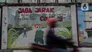 Pengendara motor melintasi mural bertuliskan protokol kesehatan COVID-19 di Kawasan Kota Bambu, Jakarta, Selasa (20/10/2020). Satgas Penanganan Covid-19 mencatat sampai  Rabu, 21 Oktober 2020, pukul 12.00 WIB warga yang terkonfirmasi positif Covid-19 bertambah 4.267 kasus. (Liputan6.com/Johan Tallo)