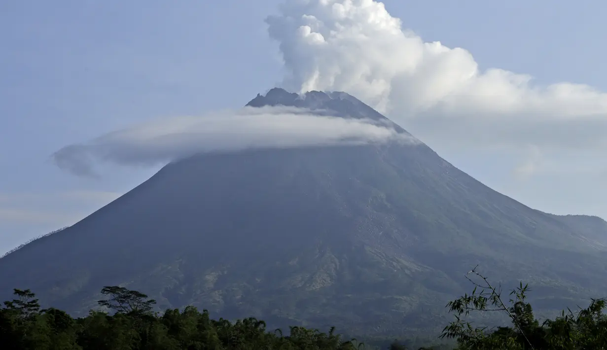 Gunung Merapi memuntahkan material  vulkanik dari kawahnya dilihat dari Sleman, Yogyakarta (7/1/2021). Kasbani mengatakan berdasarkan pantauan visual, Gunung Merapi terlihat jelas hingga tertutup kabut.  (AP Photo/Slamet Riyadi)