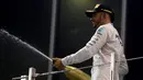 Pembalap Mercedes asal Inggris, Lewis Hamilton menyemprotkan sampanye saat merayakan kemenangan Rosberg sebagai juara Formula 1 2016 di sirkuit Yas Marina di Abu Dhabi, Uni Emirat Arab, (27/11). (REUTERS/Hamad I Mohammed)