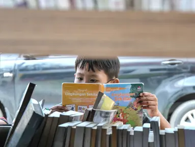 Seorang anak membaca buku di Perpustakaan Keliling kawasan Jatinegara, Jakarta, Rabu (29/9/2021). Mobil Perpustakaan Keliling yang difasilitasi Dinas Perpustakaan dan Kearsipan DKI itu merupakan sarana dan upaya pemerintah dalam meningkatkan minat baca anak sejak dini. (merdeka.com/Iqbal S Nugroho)