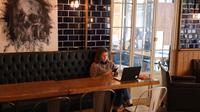 Seorang perempuan duduk dengan laptopnya di sebuah kafe di Beirut pada 14 Januari 2022. Kafe-kafe Beirut sekarang berfungsi sebagai tempat kerja pengganti bagi orang-orang yang bergulat dengan kekurangan listrik dan pemutusan internet yang berasal dari krisis ekonomi. (JOSEPH EID / AFP)