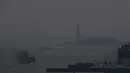 Feri Staten Island berangkat dari terminal Manhattan melalui kabut asap dengan Patung Liberty nyaris tidak terlihat, di New York, Selasa (20/7/2021). Lebih dari 60 kebakaran hutan melanda sekitar 10 negara bagian di AS, menyebabkan langit berkabut hingga New York.  (AP Photo/Julie Jacobson)