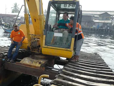 Menteri Koordinator Bidang Kemaritiman Luhut Binsar Panjaitan menaiki traktor menggelar gerakan aksi bersih di kawasan pesisir Cilincing, Jakarta Utara, Sabtu (6/4). Acara itu dalam rangka memperingati Hari Bumi. (Liputan6.com/Immanuel Antonius)