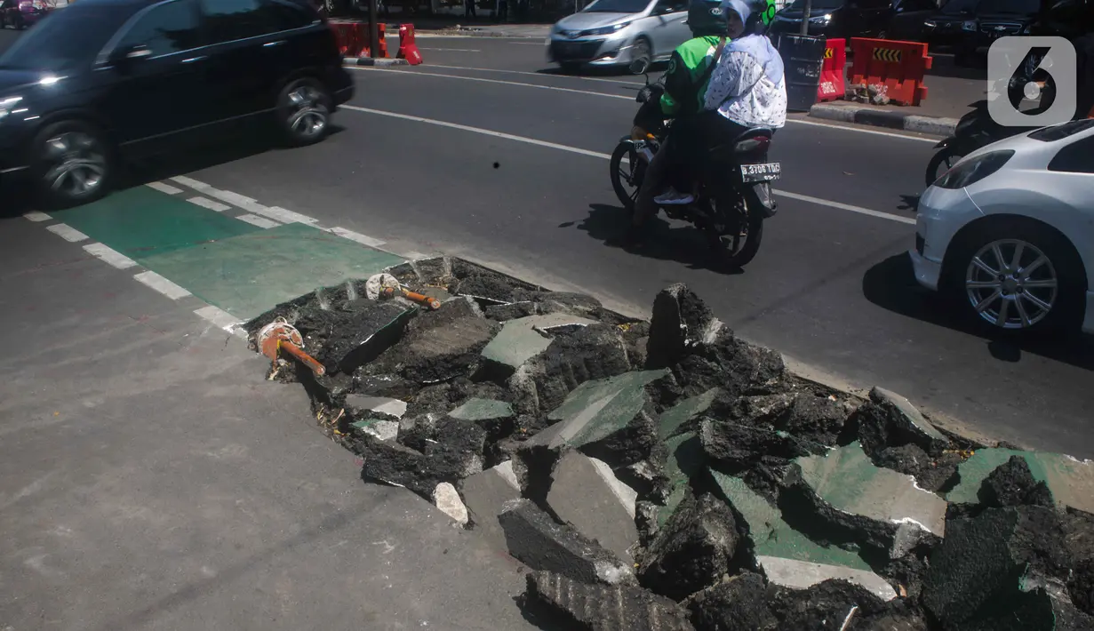 Pengguna jalan melintas di samping jalur sepeda yang di bongkar di kawasan Cikini, Jakarta, Selasa (19/11/2019). Jalur sepeda berumur 2 bulan tersebut dibongkar akibat proyek pelebaran trotoar. (Liputan6.com/Faizal Fanani)