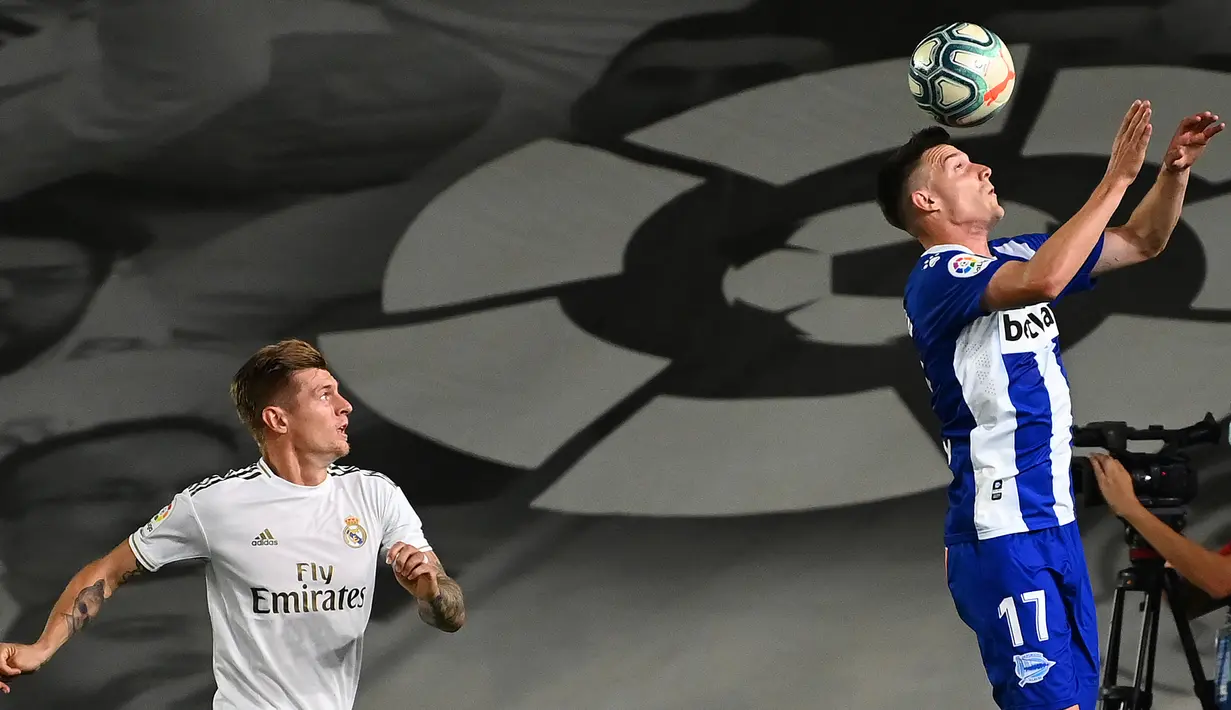 Gelandang Real Madrid, Toni Kroos (kiri) berusaha merebut bola dari bek Alaves, Adrian Marin Gomez pada lanjutan Liga Spanyol di stadion Alfredo di Stefano, Sabtu (11/7/2020). Real Madrid menang 2-0 lewat gol Karim Benzema dan Marco Asensio. (GABRIEL BOUYS/AFP)