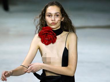 Seorang model berusaha merapikan gaun yang dikenakannya pada peragaan busana Yves Saint Laurent ready-to-wear di Paris, 28 Februari 2017. Gaun model tersebut melorot saat menampilkan koleksi Fall-Winter 2017-2018. (AP/Francois Mori)