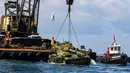 Aktivis lingkungan menurunkan tank lama ke dasar Laut Mediterania di lepas pantai kota pelabuhan Sidon, Lebanon, Sabtu (28/7). Para aktivis berharap rumput laut akan segera menutupi tank, yang merupakan hadiah dari militer tersebut. (AFP / Mahmoud ZAYYAT)